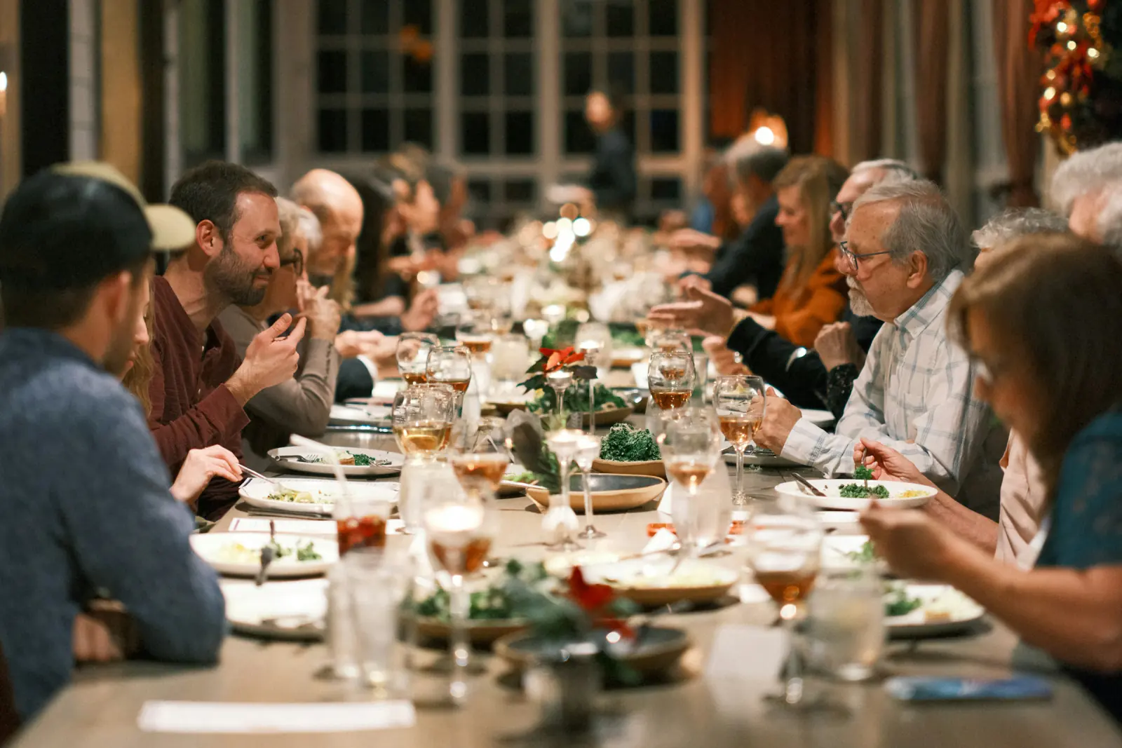 Kollegen an einer langen, festlich gedeckten Tafel in einem warm beleuchteten Restaurant