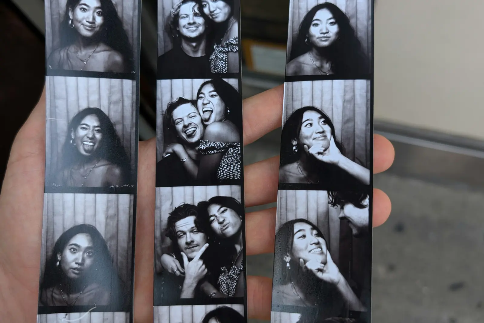 Hand hält drei schwarz-weiße Fotostreifen aus einer Fotobox