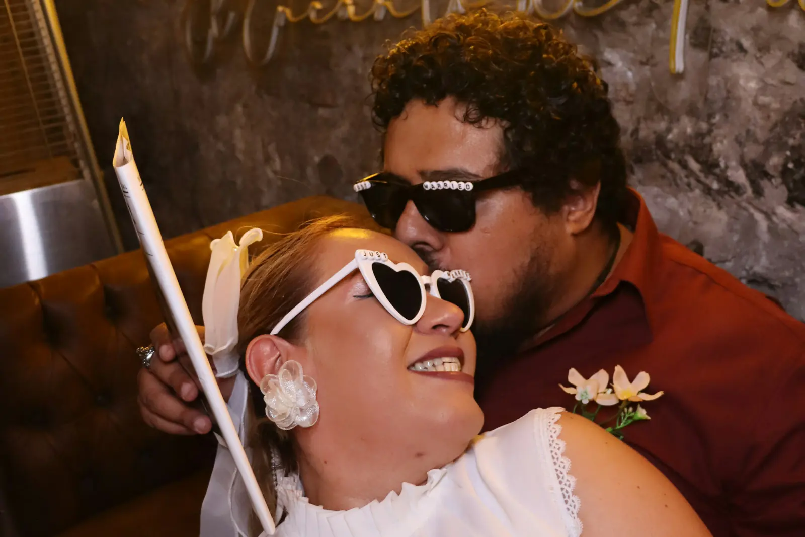 Brautpaar mit Herz-Sonnenbrille und Fotobox-Requisiten beim Kuss